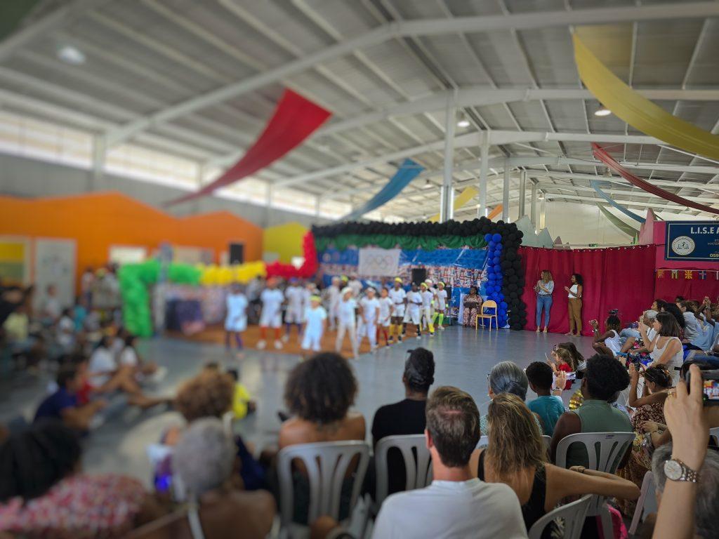 Vue d'ensemble, parents spectateurs et la scène du spectacle de fin d'année scolaire.